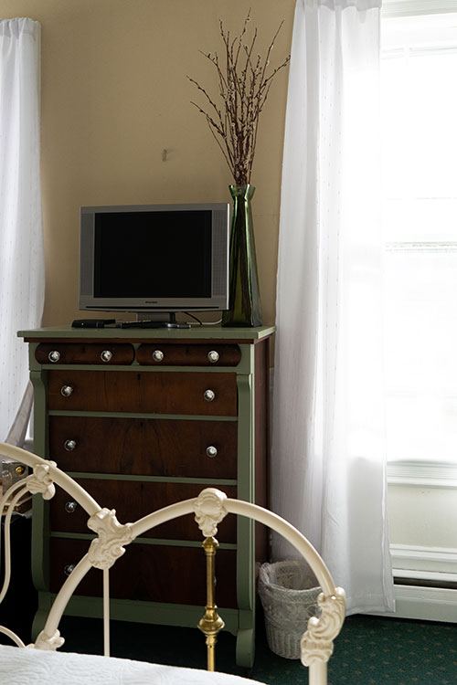 Anthony Hunsicker room: vintage television on a dresser and a white iron bed