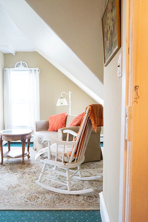 Antique Rose sitting nook with a white rocking chair under the sloped ceiling