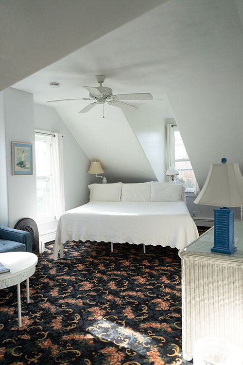 Dormer Suite attic bedroom with ceiling fan, floral rug and a blue armchair