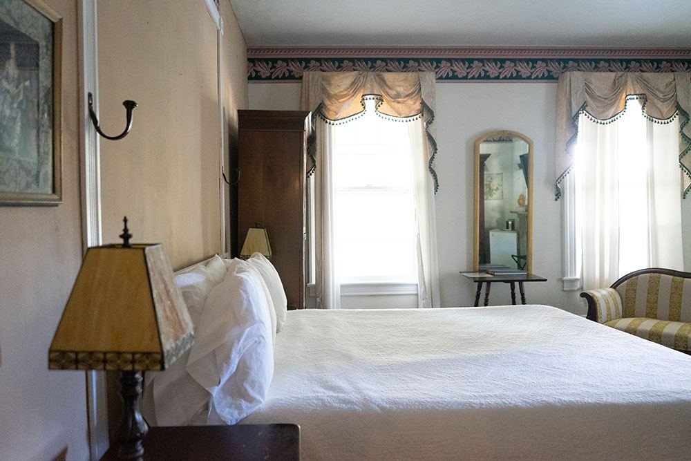 George Jacoby Suite bedroom with double bed beside a wooden wardrobe and striped armchair